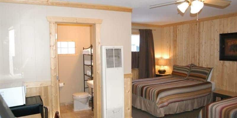 A hotel room with two beds , a toilet and a ceiling fan.