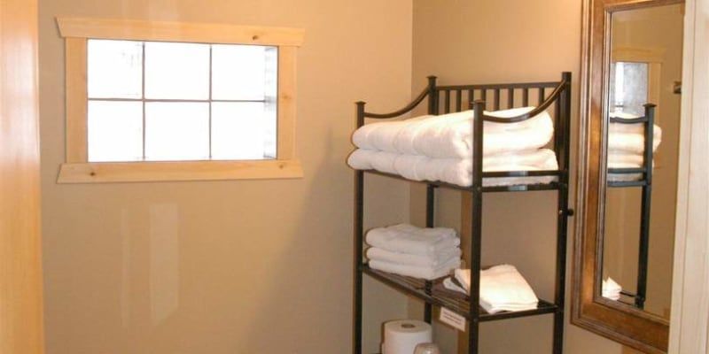 A bathroom with a shelf full of towels and a mirror.