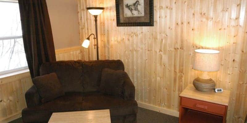 A living room with a couch , table , lamp and picture on the wall.