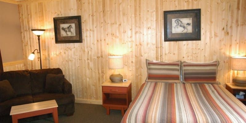 A bedroom with a bed , couch , nightstand and two pictures on the wall.