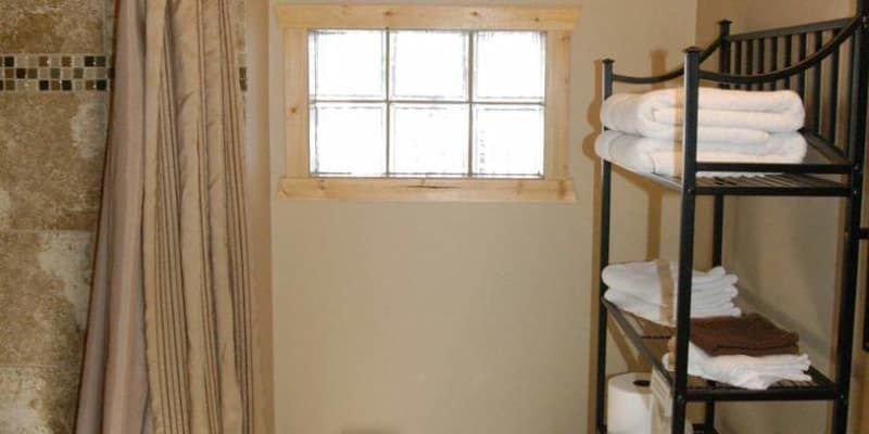 A bathroom with a shower curtain and a shelf with towels on it.