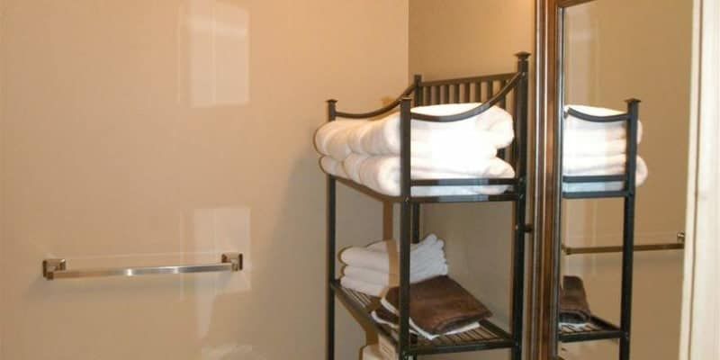 A bathroom with a shelf full of towels and a mirror.