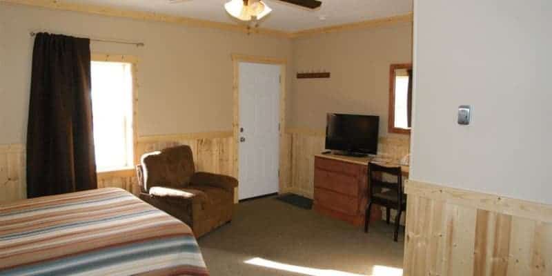 A hotel room with a bed , chair , desk and television.