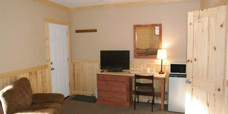 A living room with a couch , desk , chair and television.