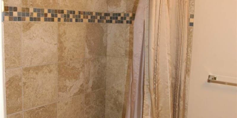 A bathroom with a shower curtain and a tiled wall.