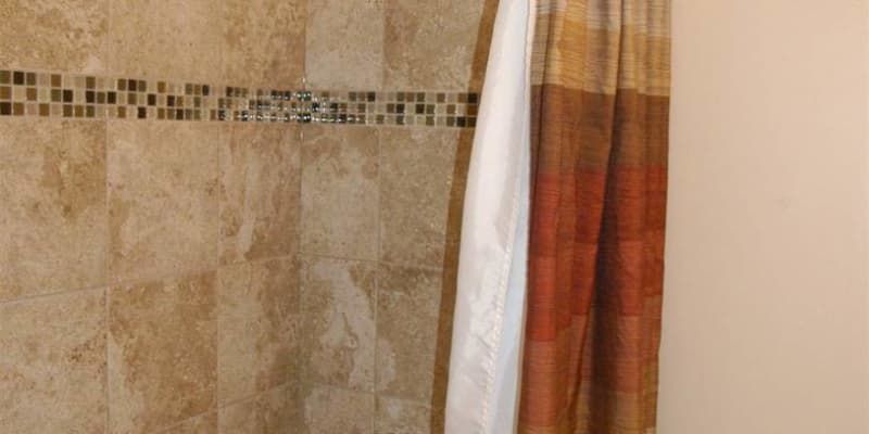 A shower curtain is hanging in a bathroom next to a tiled wall.