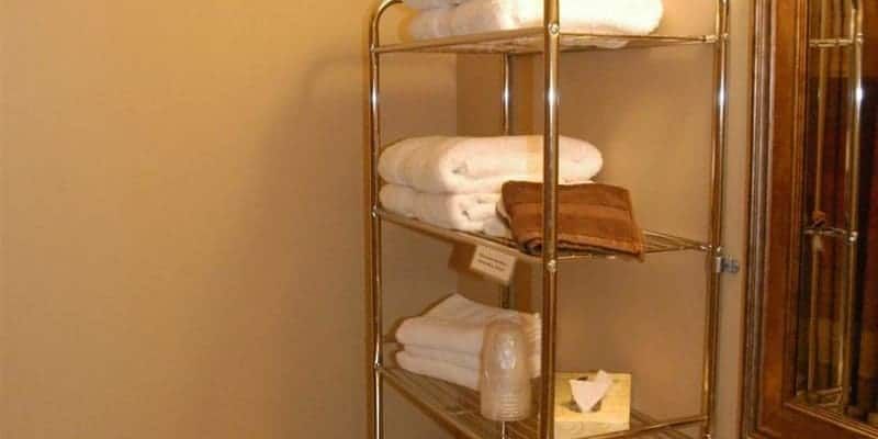 A shelf filled with towels in a bathroom next to a mirror.