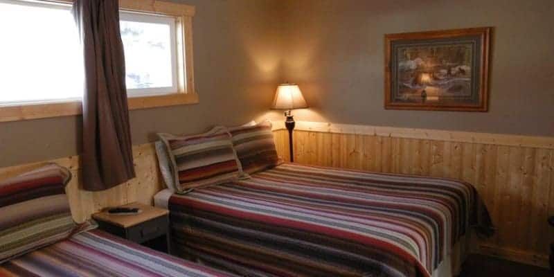 A hotel room with two beds , a lamp and a painting on the wall.