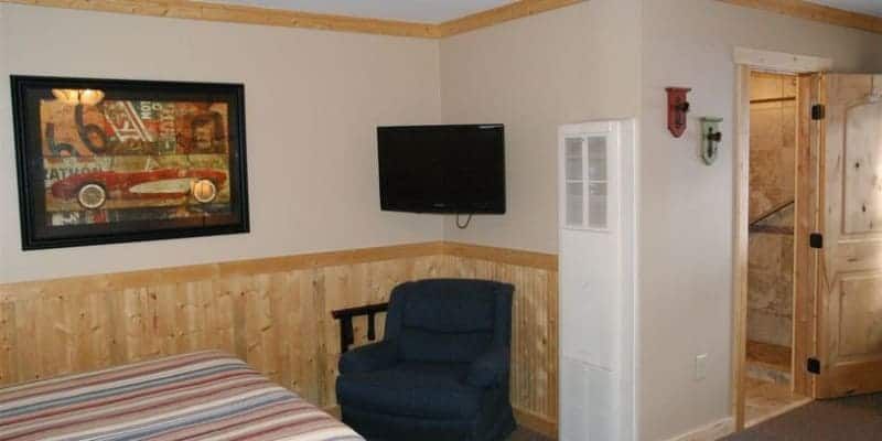 A bedroom with a bed , chair , television and a picture on the wall.