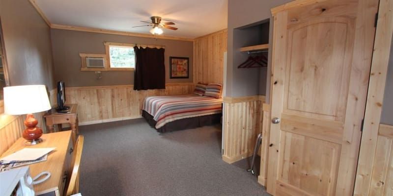 A bedroom with a bed , desk , lamp and closet.