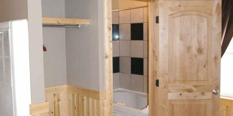 A bathroom with a wooden door and a bathtub.