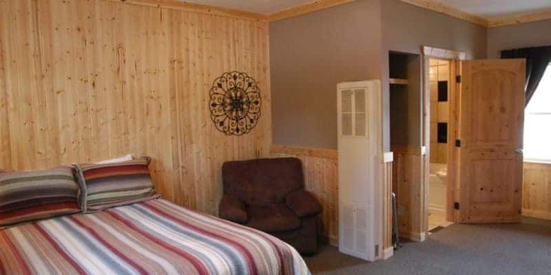 A bedroom with a bed , chair and clock on the wall.