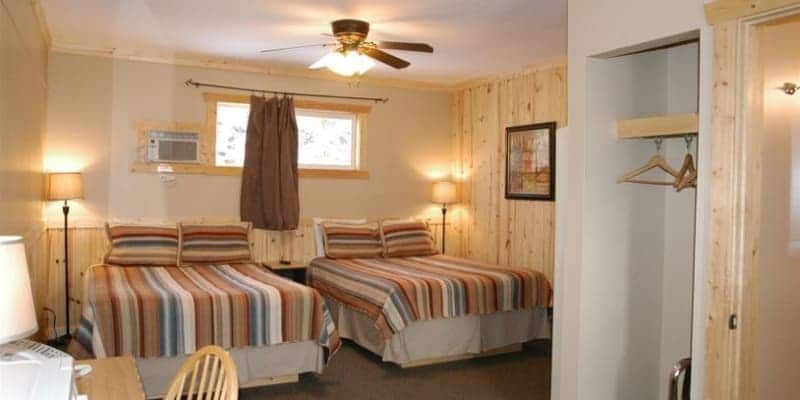 A hotel room with two beds and a ceiling fan.