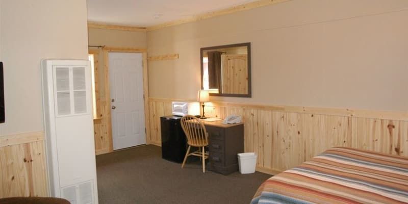 A hotel room with a bed , desk , chair and mirror.