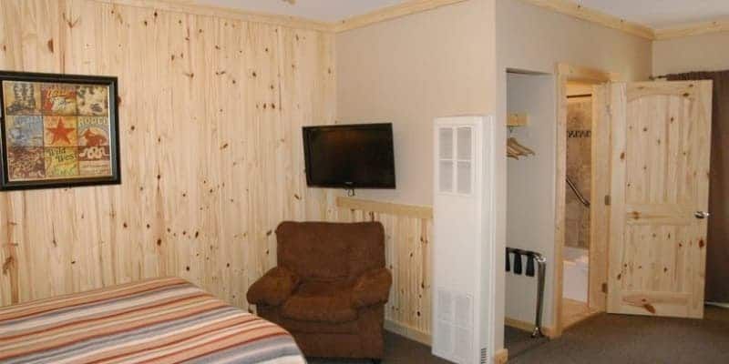 A hotel room with a bed , chair and television.