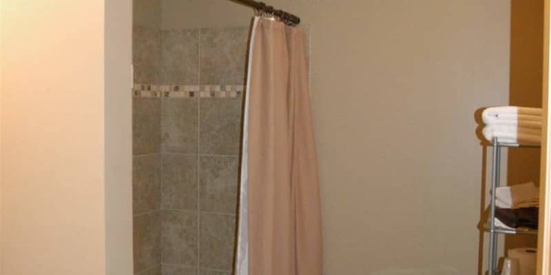 A bathroom with a shower curtain and a towel rack.