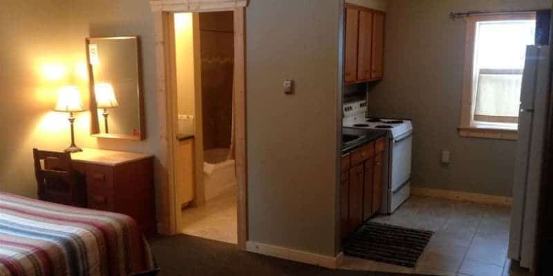 A hotel room with a bed , kitchen , and bathroom.