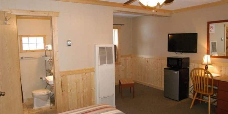 A hotel room with a bed , desk , television , refrigerator and microwave.