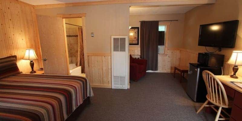 A hotel room with a bed , desk , chair and television.