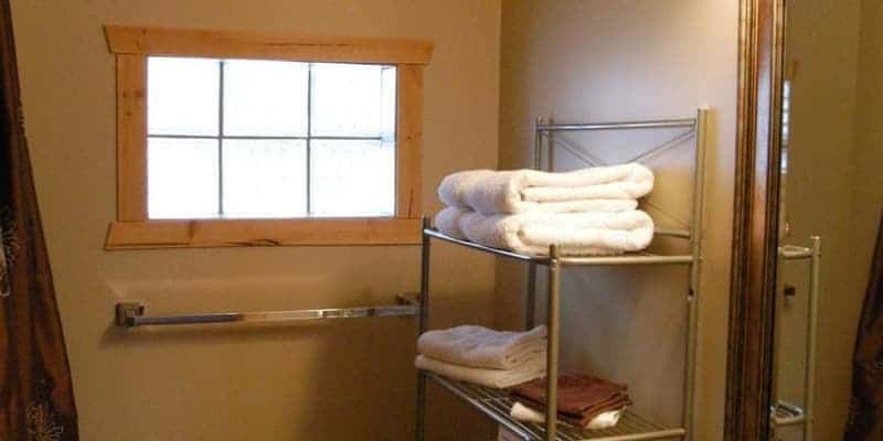 A bathroom with a shelf filled with towels and a window.