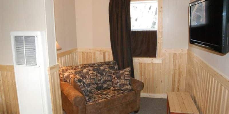 A living room with a couch and a television on the wall.