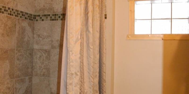 A bathroom with a shower curtain and a window.