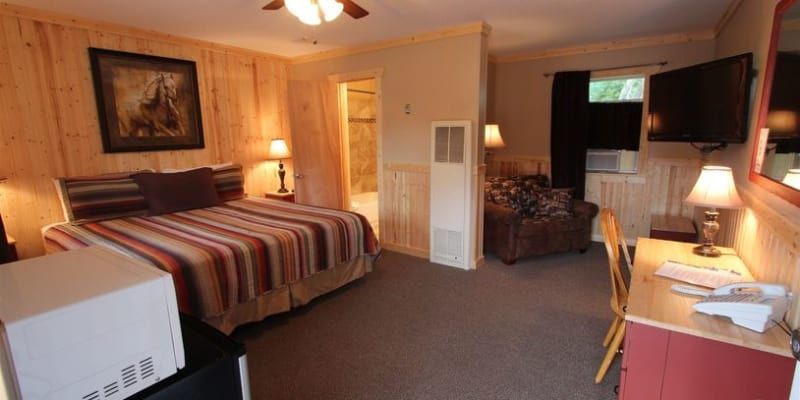 A hotel room with a bed , desk , chair and television.