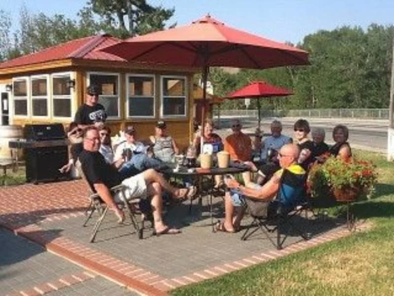 A group of people are sitting outside under umbrellas