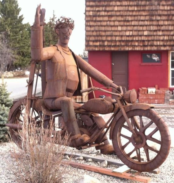A rusty statue of a man sitting on a motorcycle