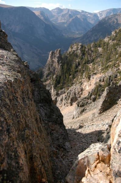 A view of a mountain valley from the top of a rocky cliff.