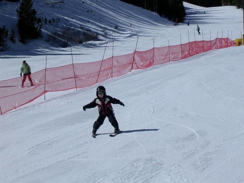 A little boy is skiing down a snow covered slope