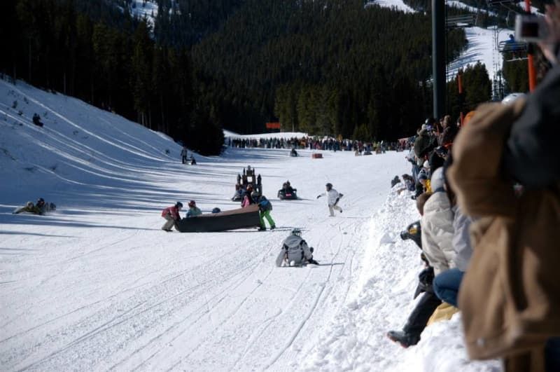 A group of people are watching skiers on a snowy slope