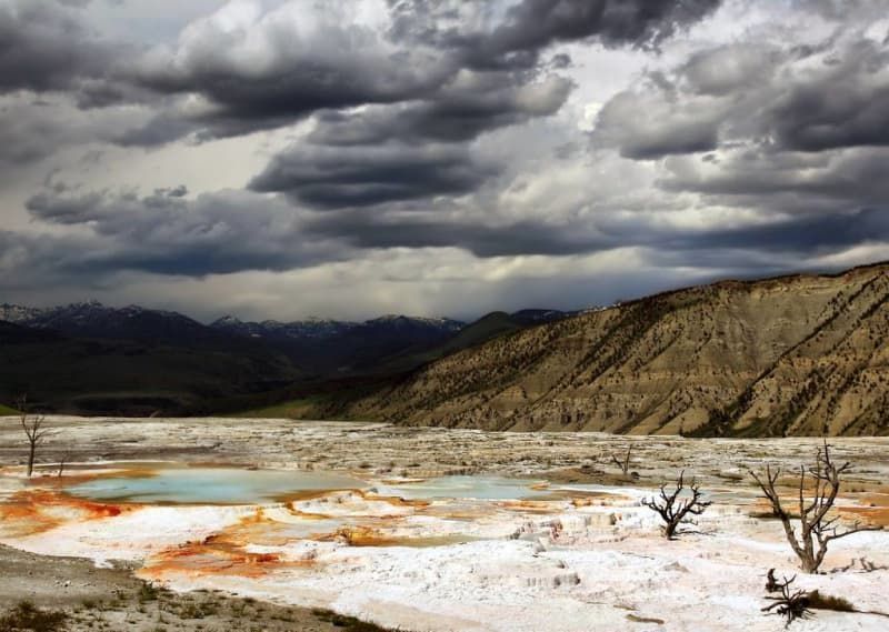 A desert landscape with mountains in the background and clouds in the sky