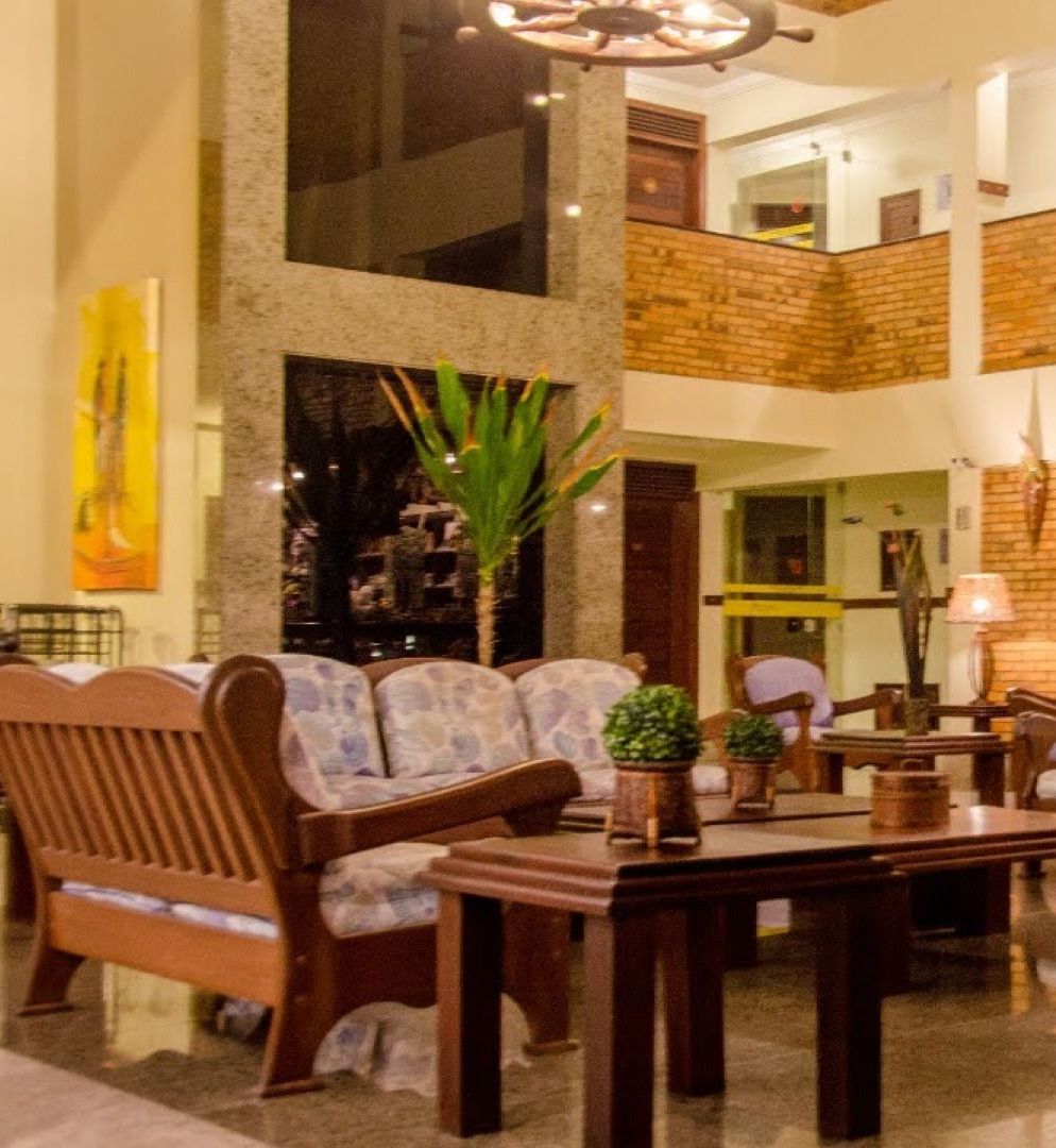 Uma sala de estar com um sofá e mesas - Pizzato Praia Hotel