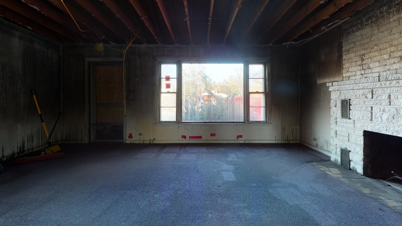 An empty living room with a fireplace and a large window.