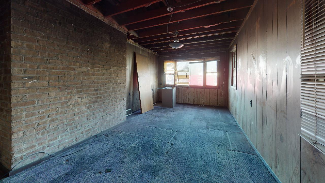 An empty room with a brick wall and a window.