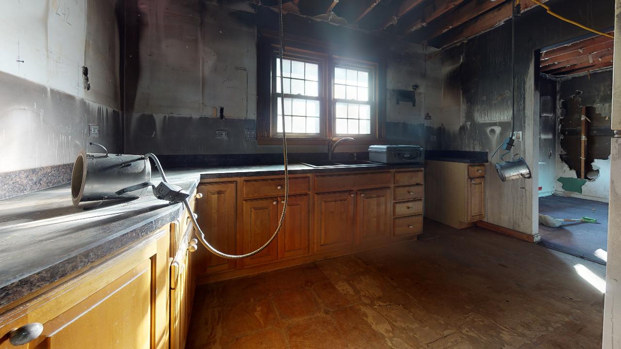 An empty kitchen with wooden cabinets and a window.