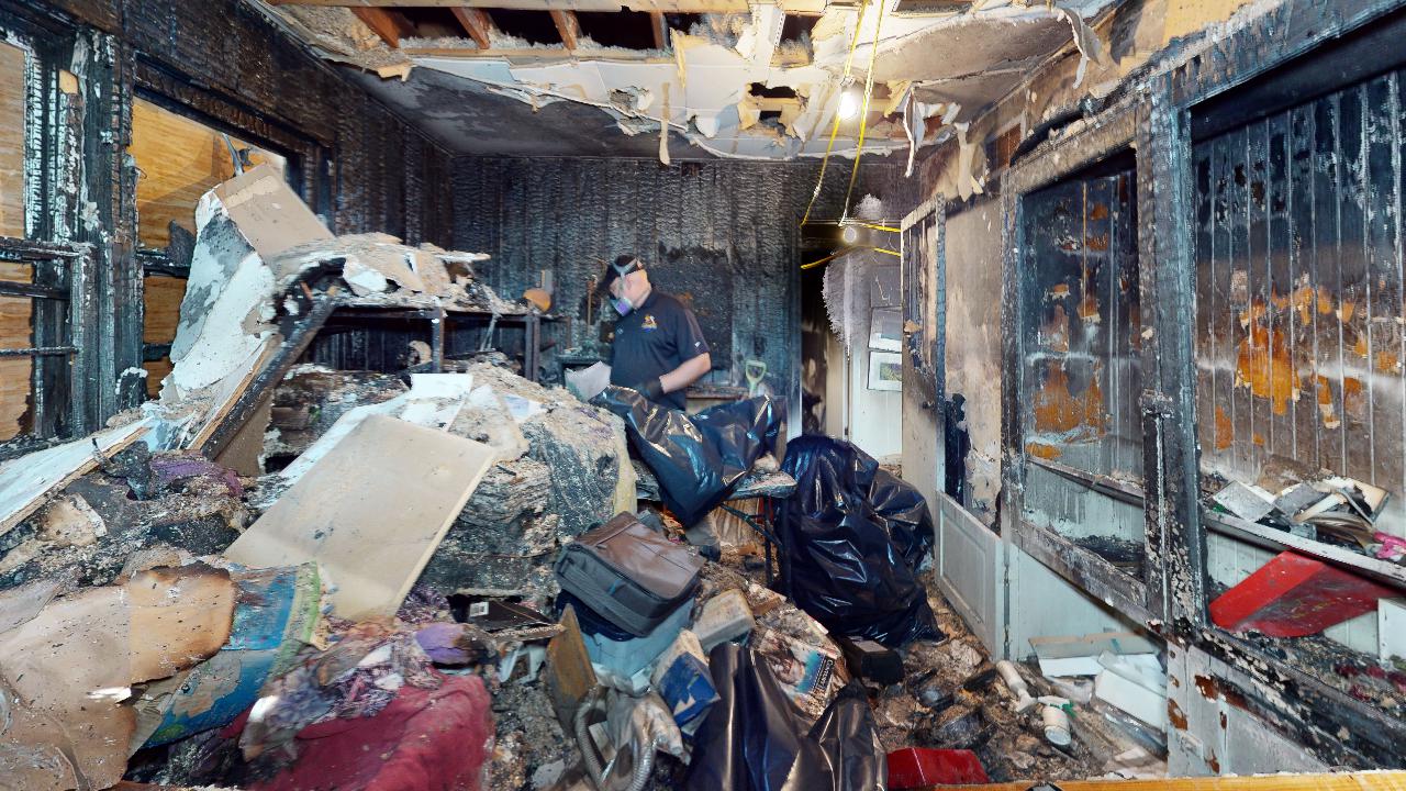 A man is standing in a room filled with lots of trash.