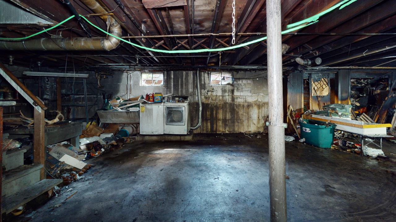An empty basement with a stove and a sink in it.