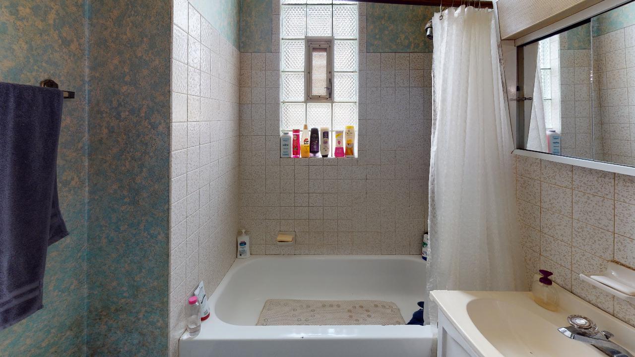 A bathroom with a tub , sink , mirror and window.