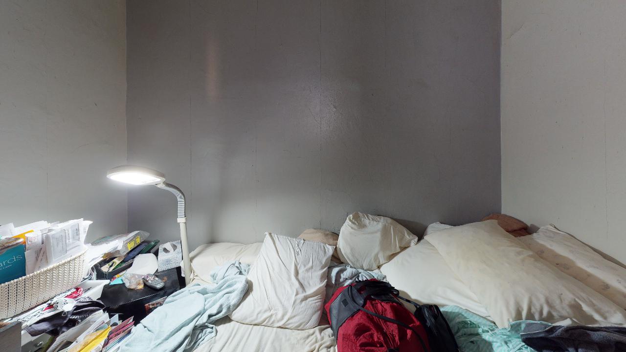 A messy bedroom with a bed and a lamp.