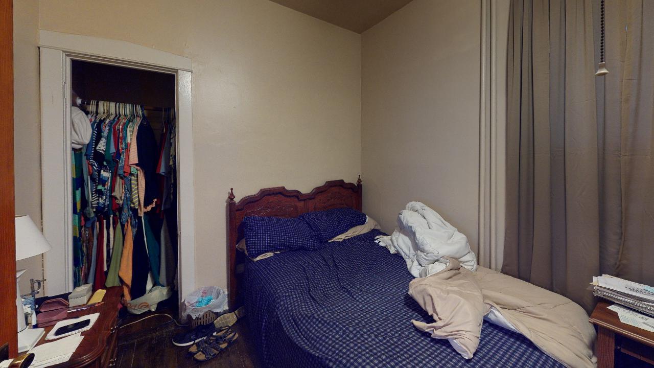 A bedroom with a bed , nightstand , and closet.