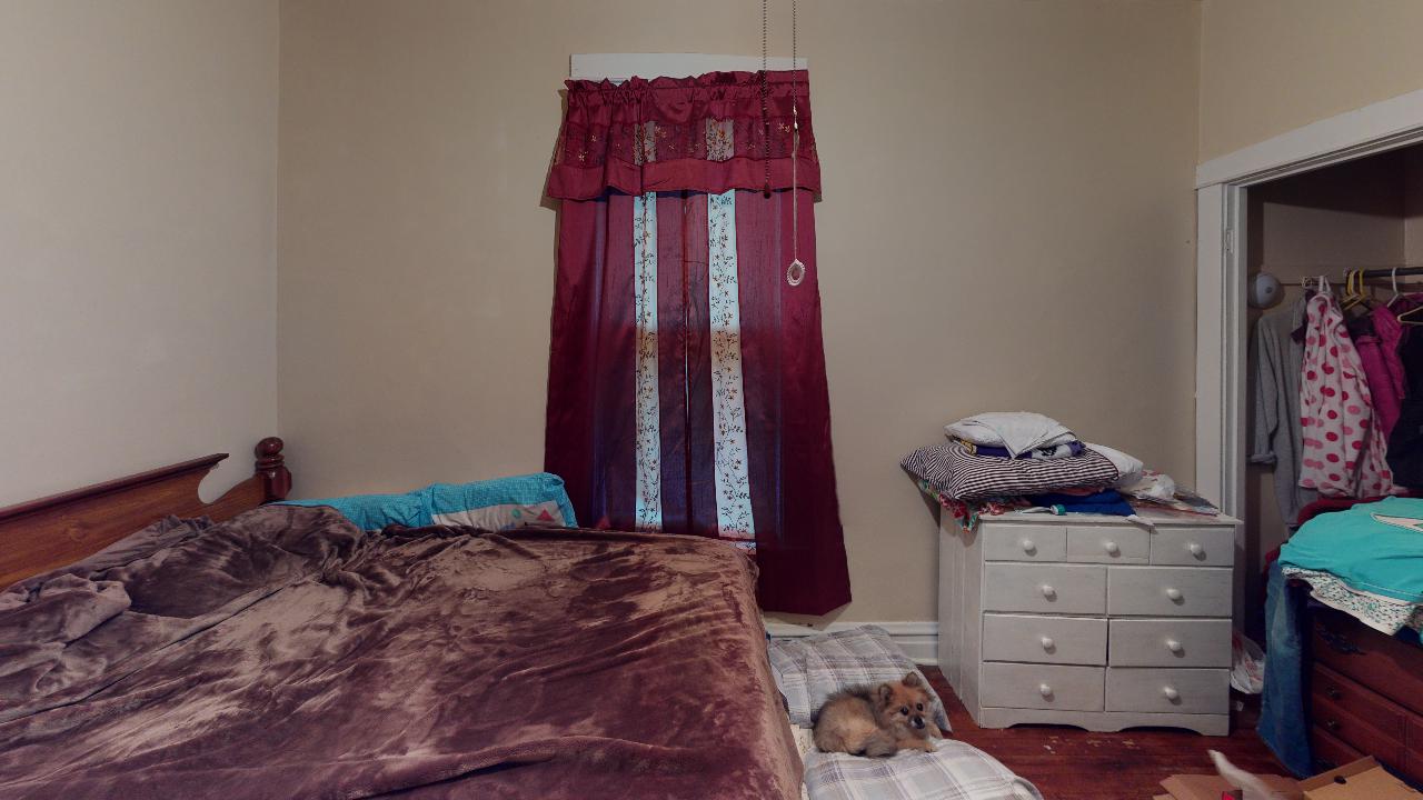 A bedroom with a bed , dresser , and window.