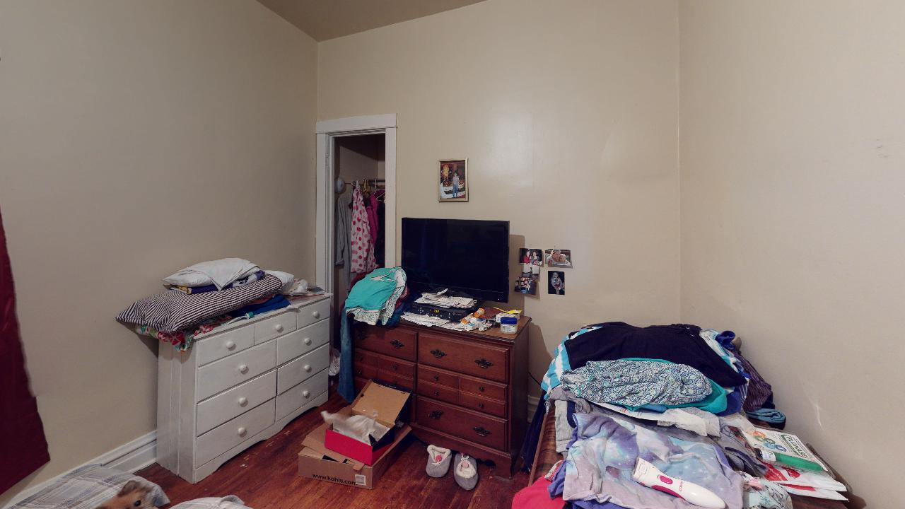 A bedroom with a bed , dresser , and television.