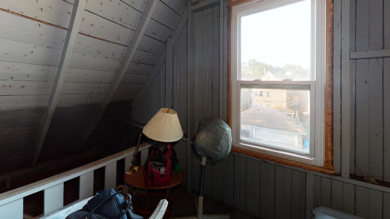 A room with a table , lamp , fan and window.