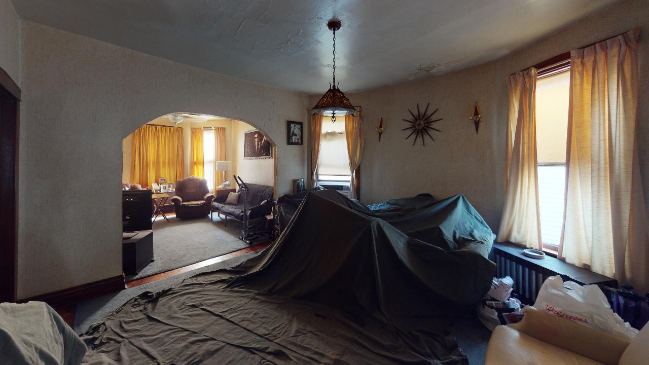 A living room with a couch covered in a tarp