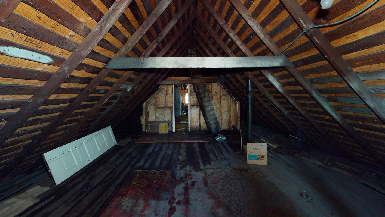 An attic with a wooden ceiling and a box on the floor.