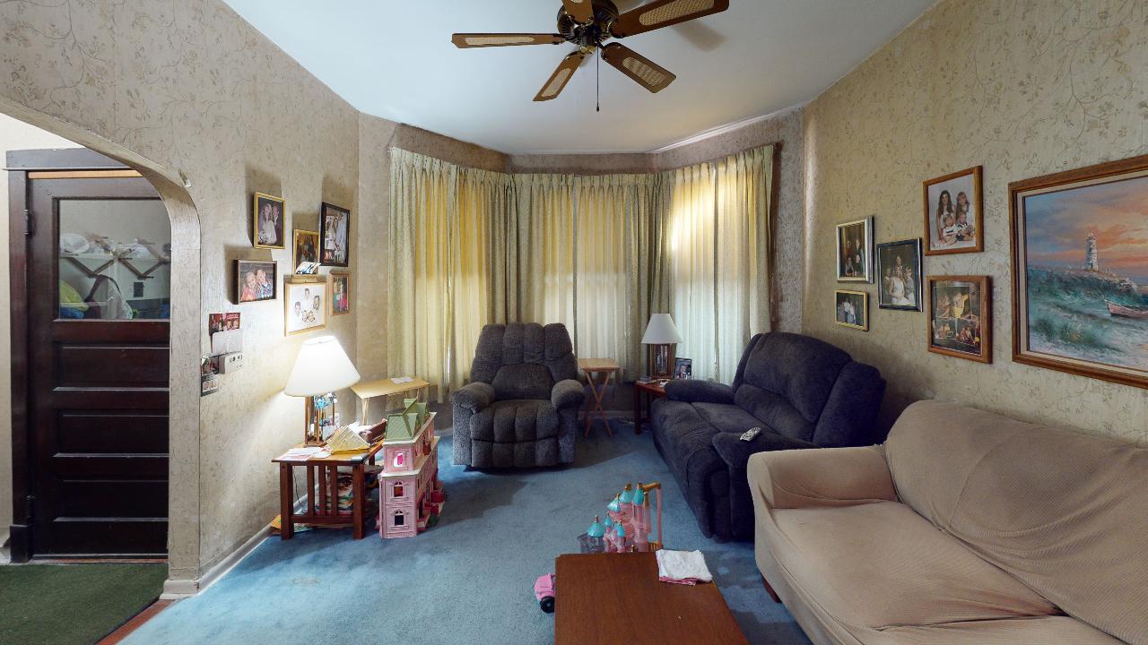 A living room with a couch , chairs and a ceiling fan.