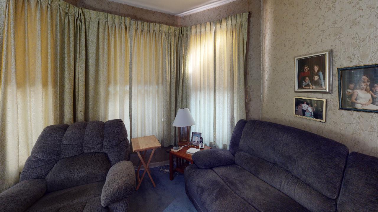 A living room with a couch , chair , table and pictures on the wall.