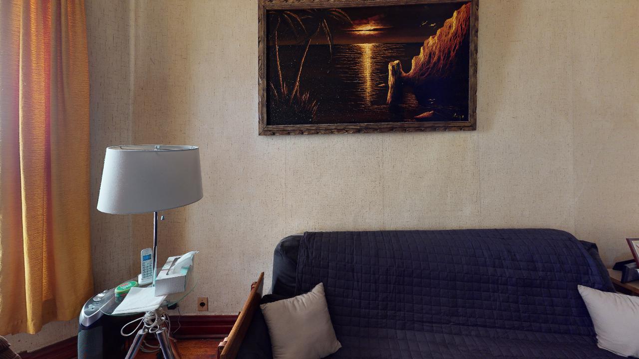 A living room with a couch , lamp , and painting on the wall.